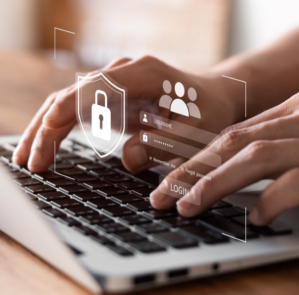 A person typing on a laptop keyboard with digital login interface and security symbols displayed above, suggesting online security measures.